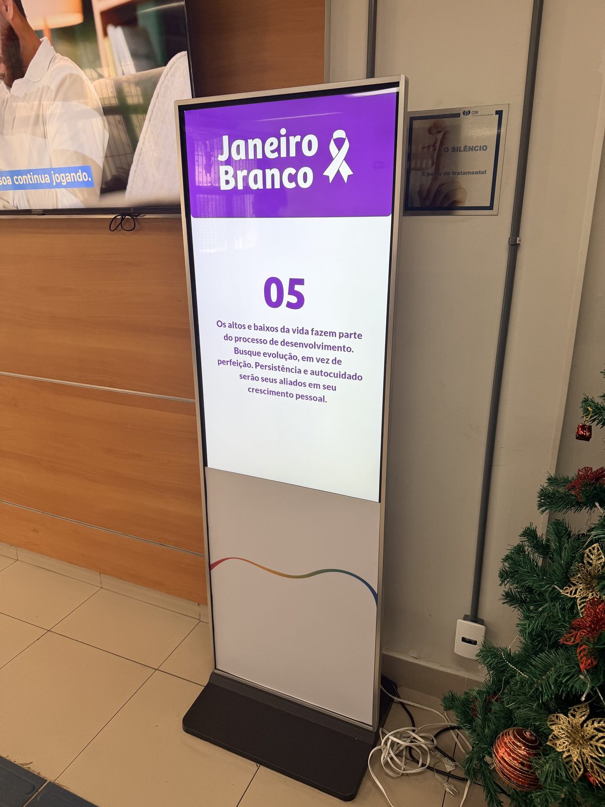 Totem digital com campanha Janeiro Branco sobre saúde mental em laboratório